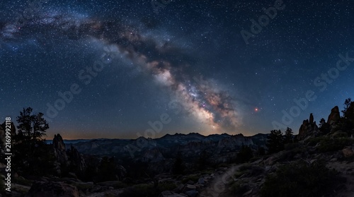 Stunning milky way galaxy arching over rugged desert mountain landscape with bright stars for night sky astrophotography.