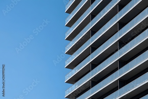 Modern Apartment Building With Repeating Glass Balconies Against Blue Sky