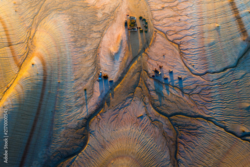 Aerial view of the striated rock formations of Kyzyl Kup, known as Tiramisu, with parked vehicles in the desert landscape of Karakiya District, Mangystau Region, Kazakhstan.