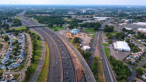Aerial view of curving multi lane highway, New Jersey. High perspective showing suburban houses, industrial buildings and green vegetation.
