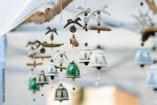 Quadro su tela Handmade ceramic bells with decorative patterns hanging at an outdoor craft market