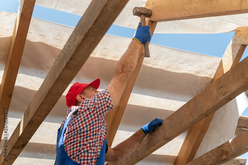 Foto Construction worker in safety gloves and workwear precisely hitting a wooden str