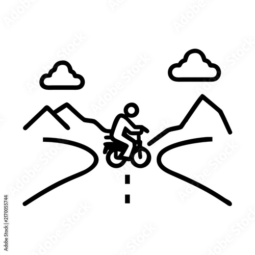 Motorcyclist traveling on a winding road among autumn mountains with a dramatic sky
