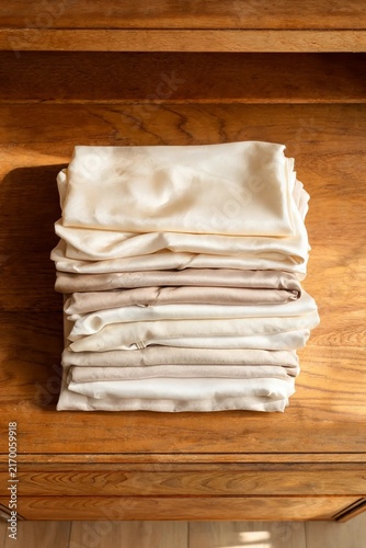 Stack of folded silk hanbok fabrics in soft traditional colors resting on rustic wooden chest