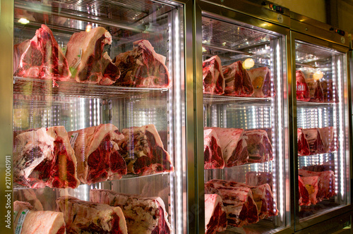 Florentina T-bone steaks dry aging inside refrigerated display in Florence