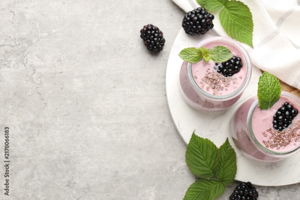 Obraz premium Tasty blackberry smoothies with chia seeds, berries and leaves on light grey table, flat lay. Space for text