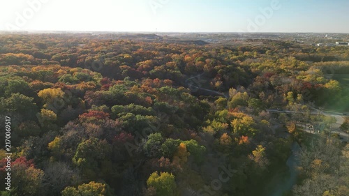 Flying out over the tree tops on a bright autumn day the trees are showing all of their fall color dotted around the hill tops of the Midwest. 4k, flying, forward