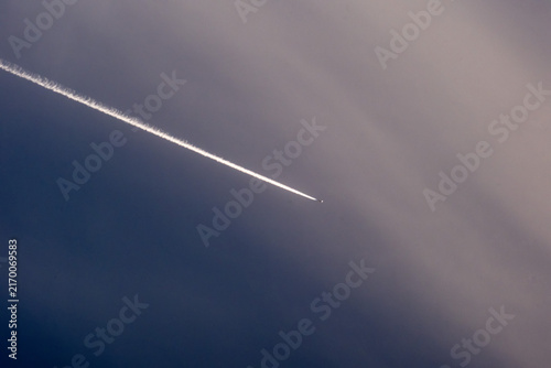 Quadro su tela Airplane in the blue sky with contrail in the air.