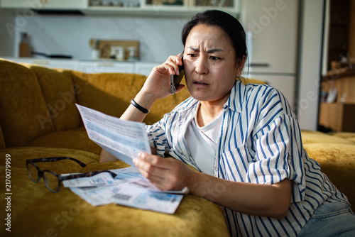 Worried woman on phone reviewing bills at home