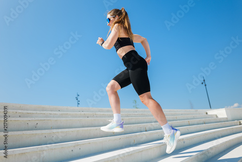 Cuadro en lienzo Energetic runner conquers outdoor stairs under a clear blue sky in a vibrant urb