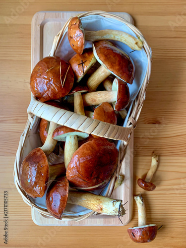 Bay bolete mushrooms in wicker basket on wooden table. Vertical top view