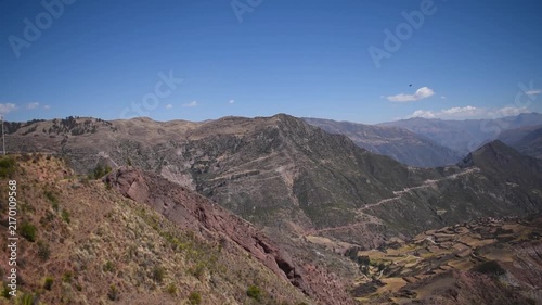 Green shrubs framing a vast Andean mountain valley in Paruro, Cusco, Peru.