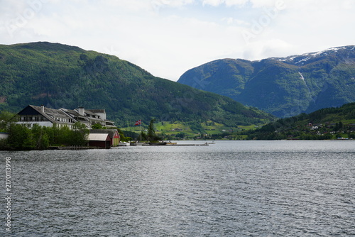 Canvas Print Norwegian fjord village with mountains rising behind calm water on a bright summer day