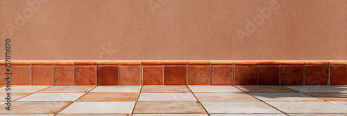Renovated interior wall with textured terracotta paint and tiled floor in modern design concept