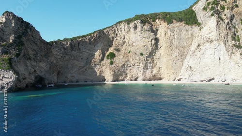 4K Aerial 180‑degree panorama shot over Chomi Beach with turquoise water and white cliffs near Paleokastritsa, Corfu, Greece