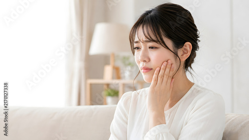 Naklejka 歯の痛みで頬を押さえる若い女性と広いコピースペース
