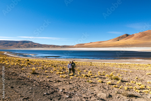 Fotografie Couple enjoying remote travel and exploration, standing by a salt flat lagoon wi