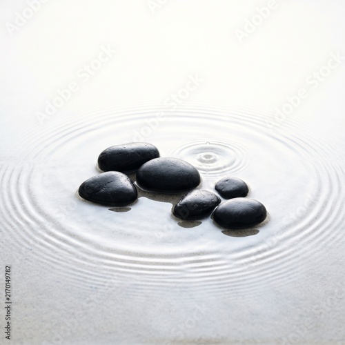 Zen rock garden stones arranged in tranquil sand ripple pattern with minimalist water ripple effect
