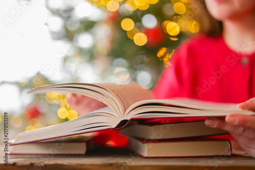 Christmas reading. Woman Reading Books Against Christmas Tree with Festive Bokeh During Christmas Winter Holidays.literacy campaigns,bookstore promotions