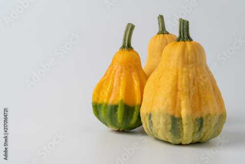 Foto Three yellow and green decorative gourds grouped on the right side of a clean light gray background with generous copy space