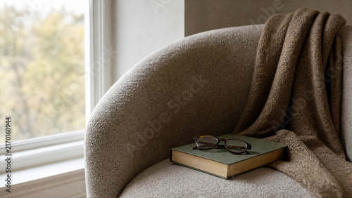 Cozy nook with a book and glasses on a chair near a window