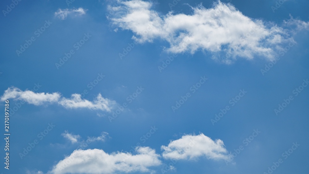 Fototapeta premium Bright Blue Sky with Fluffy White Clouds on a Sunny Day Background with Central Copy Space