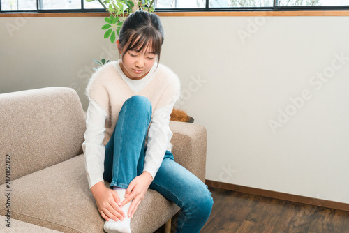 Canvastavla Elementary and middle school girls sitting on a sofa at home, holding their ankles