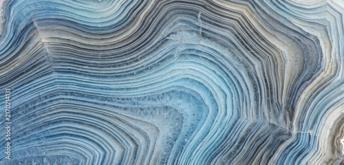 Close-up of a natural stone surface showcasing unique blue and gray banding patterns, highlighting the intricate layers and textures of geologic formation.