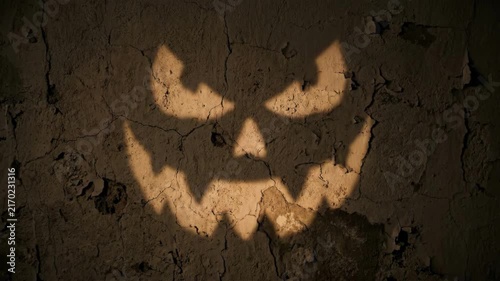 Cinematic 4K Seamless Loop of a Scary Glowing Jack-o'-Lantern Face Shadow Flickering on a Dark Cracked Haunted Wall