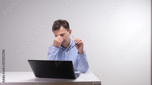 Принти на полотні Tired man feeling eye strain and headache at his desk, holding eyeglasses while