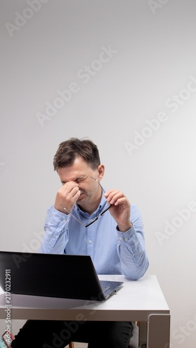 Obraz na płótnie Man suffering from headache and eye strain while working intensely on a laptop a