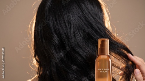 Close-up of woman's smooth, shiny black hair, highlighted by a hair care product bottle, suggesting healthy beauty routines and effective treatment