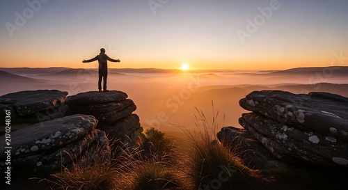Person standing with arms wide open on rocky mountain top at sunrise, mountain