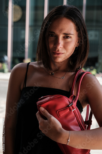 Photography Woman holding red handbag looking at camera outdoors