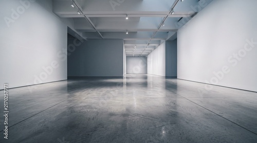 A long, empty, modern art gallery hallway with white walls and a reflective concrete floor, illuminated by ceiling lights.