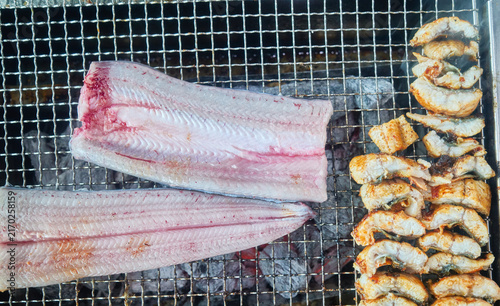 Fotografie Premium raw eel fillets roasting over a hot charcoal grill capturing an authenti