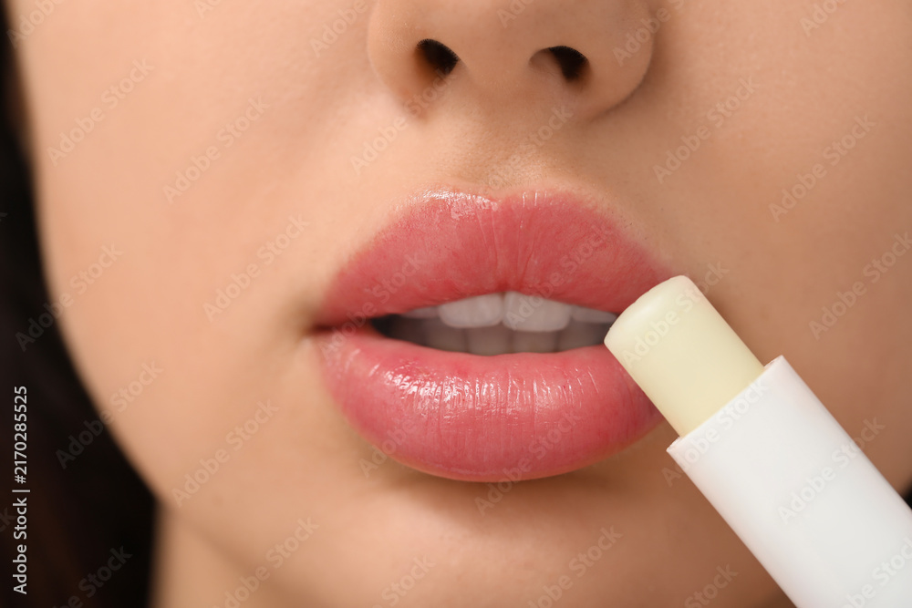 Naklejka premium Young woman applying lip balm, closeup