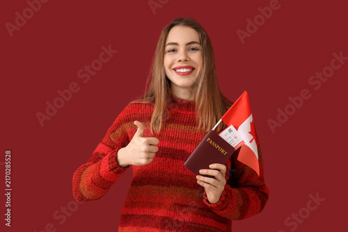 Beautiful young happy woman with Canadian flag, passport and ticket showing t...
