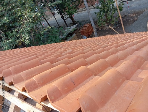 Fotografía Orange terracotta clay roof tiles on wooden structure during residential house c