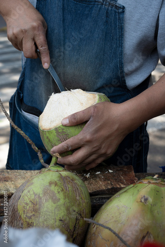 a man holds a ripe coconut cut to drink