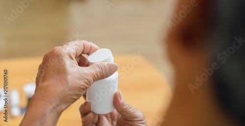 Close-up of an elderly person hand opening a medicine bottle at home, medication and healthcare.