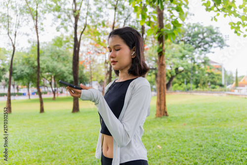 Bild auf Leinwand Asian sporty woman open speakerphone talking with friend on smartphone in public
