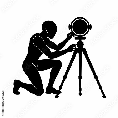 Black silhouette of a technician wearing a helmet kneeling to operate a surveying instrument or professional camera on a tripod, isolated on a white background for design.