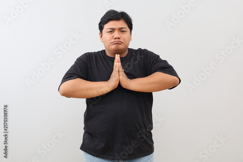 Cuadro en lienzo An overweight man appears to be pleading or asking for something with his hands clasped in front of his chest; the image was taken in a studio against a white background