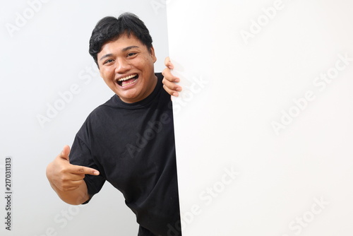 Foto A studio photo of a heavy-set man pointing at a large, blank white board—providing space for promotional text or images—while giving a thumbs-up, set against a white background