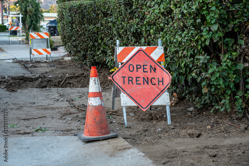Obraz na płótnie Construction zone with open trench warning sign and traffic cone