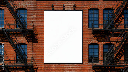 Blank white advertisement board on red brick factory wall with fire escape. Urban outdoor advertising space mockup. City building facade template.