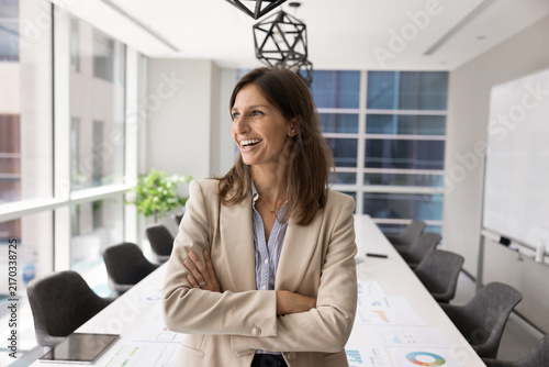 Bild auf Leinwand Smiling adult Latina female corporate executive standing with arms crossed in mo