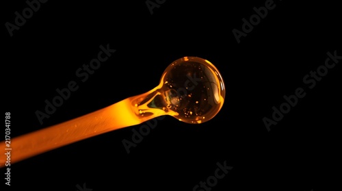 Macro shot of glowing molten glass forming a transparent bubble drop against a black background