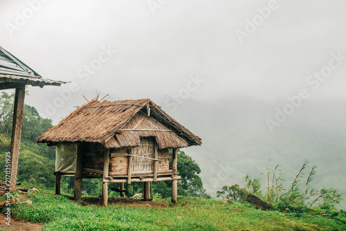 Cuadro en lienzo Traditional raised bamboo hut with a thatched roof overlooking a misty mountain